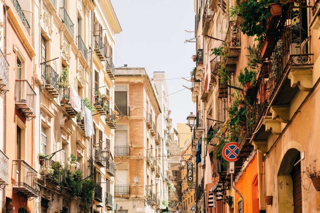 A beautiful alley in Sardinia with historic buildings and balconied plants.