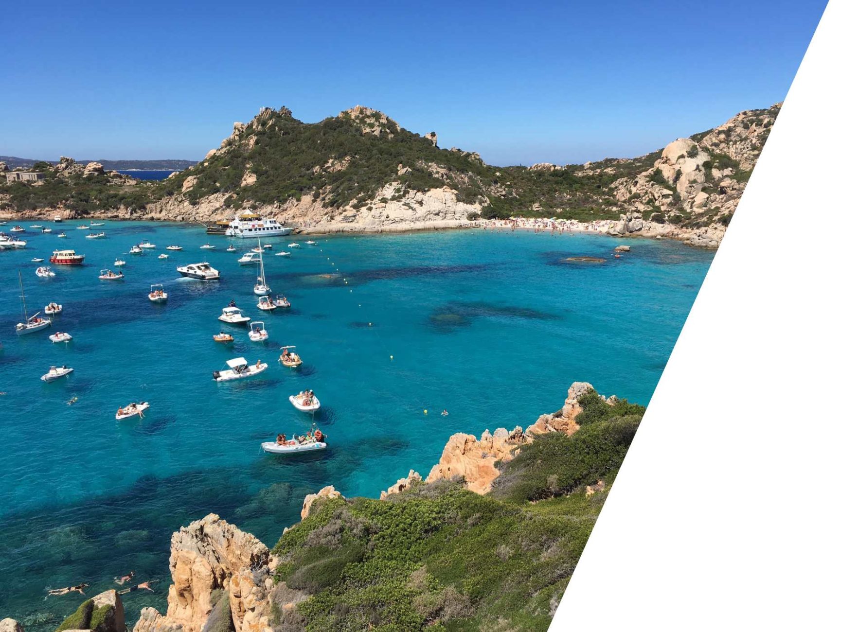 A bay in Sardinia with turquoise blue water, numerous boats, and a rocky coastline.