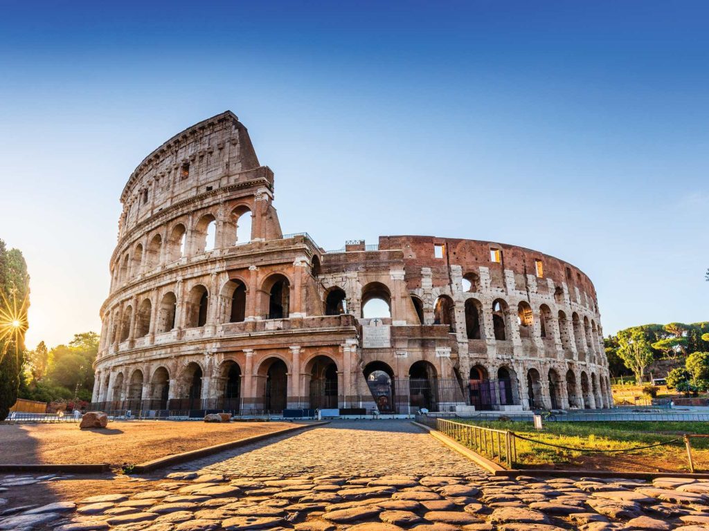 The Colosseum in Rome under a blue sky.