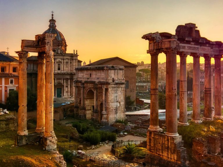 Roman Forum at sunset with ancient temple columns and historical buildings.