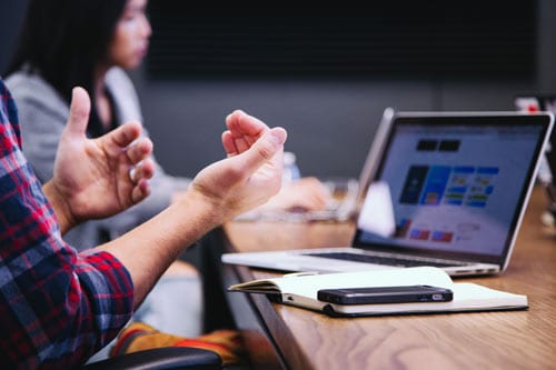 a hand is showing signs while having a laptop in the background