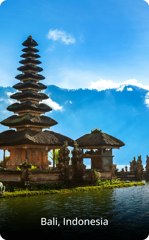 Temple by the water in Bali, featuring traditional Balinese architecture reflected in the calm surface of a lake or sea.