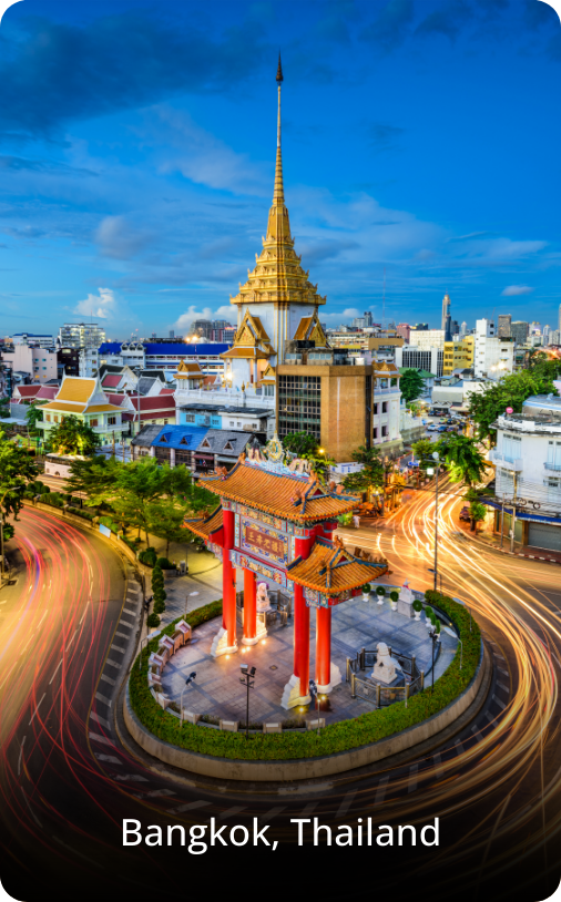 Roundabout in Bangkok at night with city lights glowing and buildings illuminated in the background.
