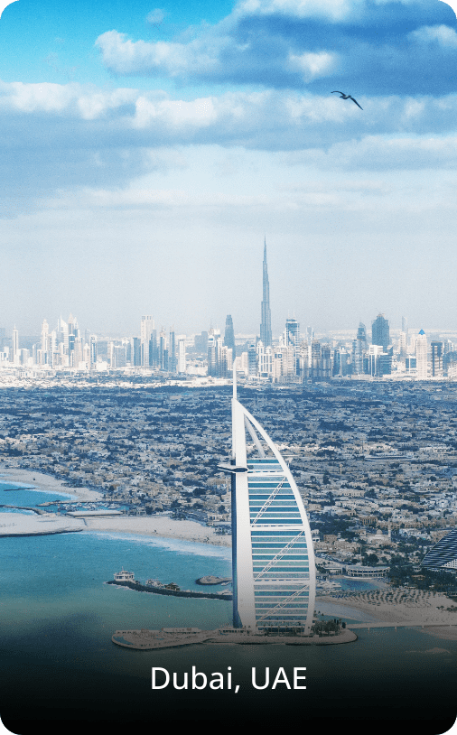 Aerial view of Dubai featuring the city skyline and coastline, with skyscrapers rising near the blue sea under a clear sky.