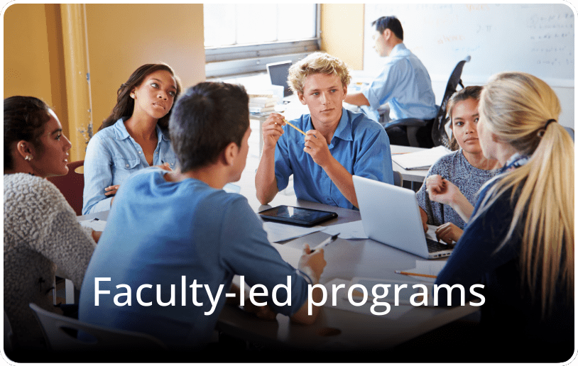Students studying around a table in a collaborative setting, with the text “Faculty-Led Programs” overlaid on the image.