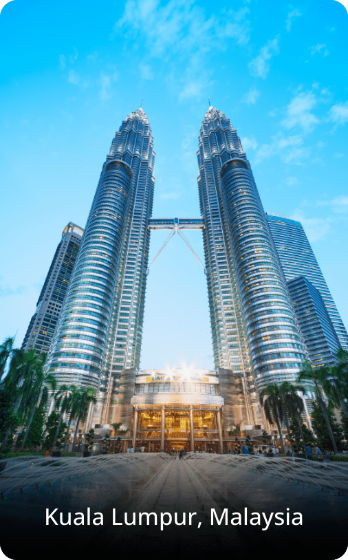 The Petronas Twin Towers in Kuala Lumpur, Malaysia, rising above the city skyline with modern glass architecture under a bright sky.