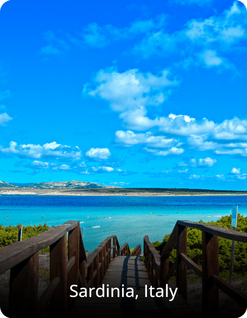 Scenic beach in Sardinia, Italy, with a staircase leading down toward turquoise water and soft white sand.