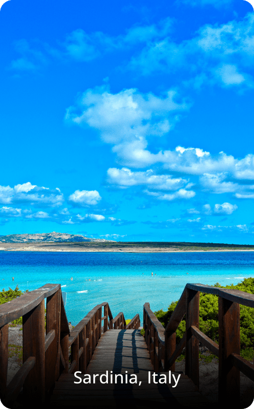Scenic beach in Sardinia, Italy, with a staircase leading down toward turquoise water and soft white sand.